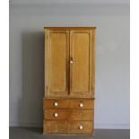 A Victorian pine cupboard over chest, the short plain cornice over two long panelled doors opening