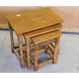 A reproduction oak nest of tables, with turned supports, the smallest with nulled frieze 53cm x 58cm