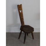 A carved oak spinning chair, the tapering back guilloch carved with pierced heart motif, the