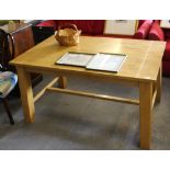 A modern light wood refectory style table, the rectangular top raised on four angled legs linked