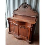 A Victorian mahogany serpentine fronted chiffonier, the shaped back with carved fruiting vine