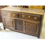 A 19th century oak dresser base, the oblong top above two drawers and two panelled doors, the