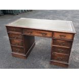 A late Victorian oak kneehole pedestal desk, the top with later tooled green leather, fitted nine