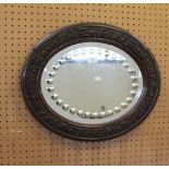 A 1920's oval wall mirror, the bevelled plate with a band of convex roundals, the framed moulded