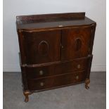 A 1940's mahogany cupboard, having a shallow raised back with scrolled decoration over the