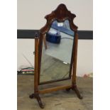 A 1920's figured Queen Anne style dressing mirror, with shaped arched surmount between slender acorn