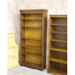 A tall reproduction mahogany bookcase, with moulded and dentil carved cornice above adjustable