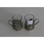 A pair of plated and clear glass mulled wine glasses, the holders moulded and pierced with