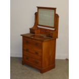 An Edwardian walnut dressing chest, the rectangular mirror plate between arched and pierced supports