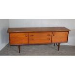 A 1970's Younger teak sideboard with three central drawers, enclosed by end cupboards, one bearing