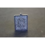 An imported silver ingot style pendant, decorated with knotted central motif and foliage, with