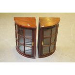 A pair of glazed mahogany corner cupboards, of bowed quadrant form, each with nine glass panels,