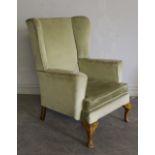 A green dralon upholstered wing back fireside chair 96cm marks to legs.