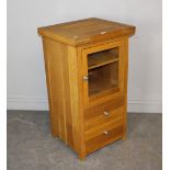 A modern light oak music/media cabinet, with glazed and hinged door over two drawers 92cm x 50cm x