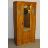 An Edwardian walnut mirror door wardrobe, the arched bevelled plate between slender panels with
