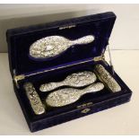 A late Victorian silver-backed five-piece dressing table brush set, embossed with foliate scrolls