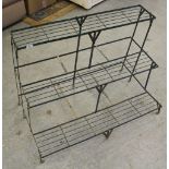 A metal three-tier plant stand, green painted 75cm x 97cm x 60cm some corrosion.
