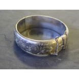 A silver bangle, of hinged circular form with foliate engraving, 7cm, 29grams, tarnishing, generally