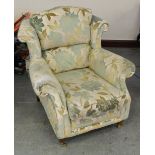 A modern wing-back armchair, with scrolled wings and arms covered in foliate patterned upholstery