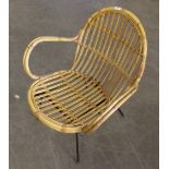 A vintage cane open armchair, with black painted metal legs