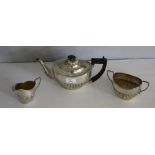 A silver three-piece tea set, comprising a teapot sugar and cream, of ovoid form with half gadrooned