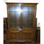 Reproduction oak two door bookcase on base enclosing two cupboards, 144cm wide. We are unable to