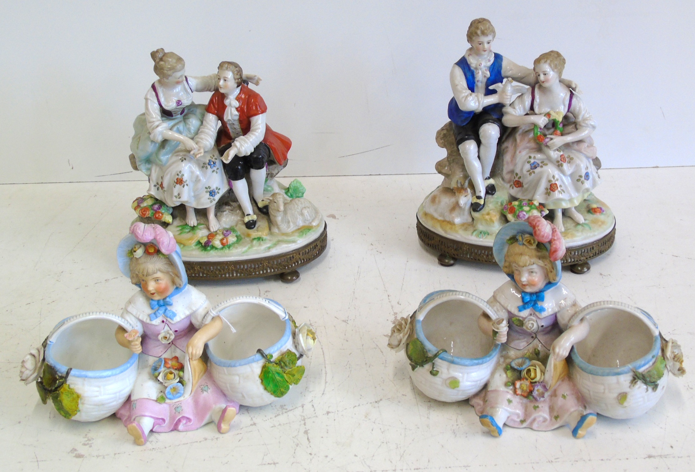 A pair of continental porcelain Vienna style figure groups and a pair of bisque bon bon dishes 20 cm