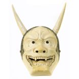 A Japanese Meiji Period carved ivory mask netsuke depicting Hannya, typically carved with bared