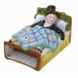 Goss matchbox holder modelled as a gentleman asleep in bed, playing cards scattered across the bedsh