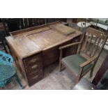 Mid 20th century stained oak typists desk and an oak open armchair.
