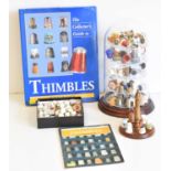 Collection of thimbles contained under a plastic dome including several cast metal circus figure thi