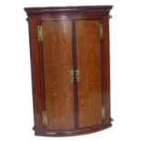 George III oak two-door bow front corner cupboard.