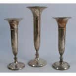 A set of three silver trumpet vases, the central taller vase flaked by two smaller vases, with