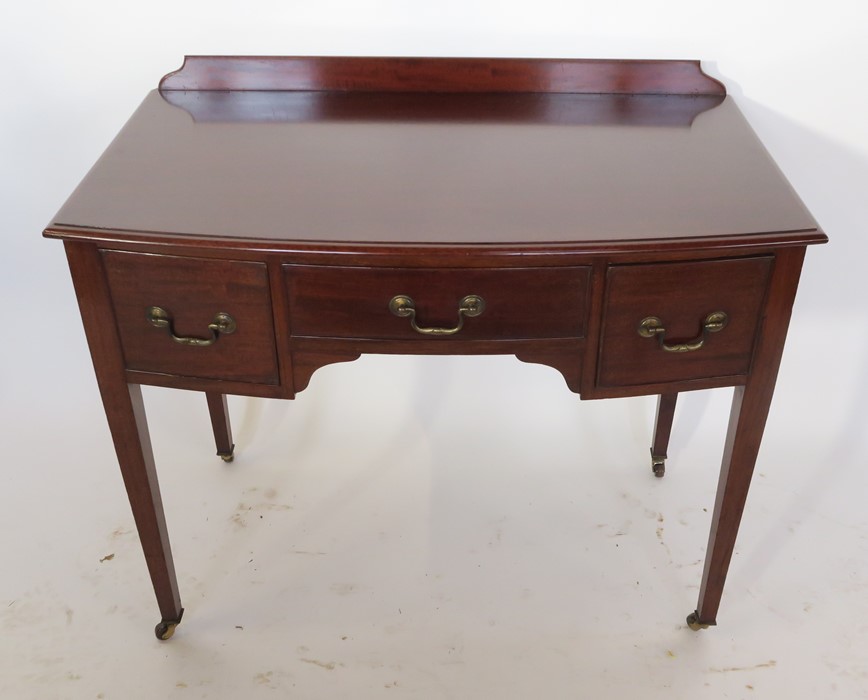 An early 20th century Heal's bow front mahogany knee-hole dressing table, with three drawers,