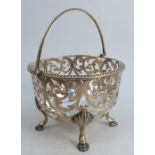 A pierced silver basket, with swing handle, having engraved pierced decoration, raised on four