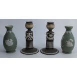 A pair of Wedgwood jasper ware candlesticks, decorated with classical motifs to a black ground,