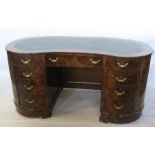 A walnut veneered kidney shaped kneehole desk, with tooled leather inset writing surface, fitted