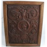 A carved oak panel, decorated with urn of fruit, faces and mythical beasts, 18ins x 13.5ins
