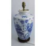 An Oriental style porcelain lamp base, decorated in blue and white with flowers, on a wooden base,