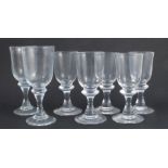 Five drinking glasses, together with a pair of slightly larger similar glasses, all with knop stems,