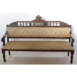 A stained pine upholstered settee, the carved and upholstered back with mirror panel, length 72.