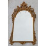 A gilded plastic framed wall mirror, decorated with an urn of flowers and scrolls, overall