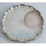 A silver tray, with shaped ogee border, engraved with initials and raised on three knurl feet,