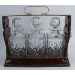 A Betjemann's Patent walnut three bottle tantalus, with silver plated hinged top and mounts, with