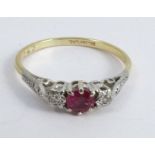 A ruby and diamond three stone ring, stamped '18ct Plat', the round cut stone between illusion set