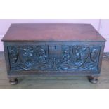 An Antique oak bible box, having a plain rising lid, floral carved to the front and raised on ball