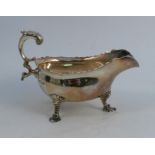A Georgian silver saucer boat, with shaped edge, double scroll handle and raised on three legs,