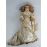 A continental bisque headed doll, dressed in 19th century clothes, length approximately 19ins