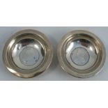 A pair of silver circular dishes, the bases set with coins, Birmingham 1930, weight including