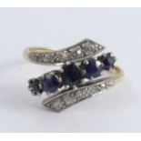 A sapphire and diamond cross over ring, stamped '18ct Plat' with a central line of five graduated